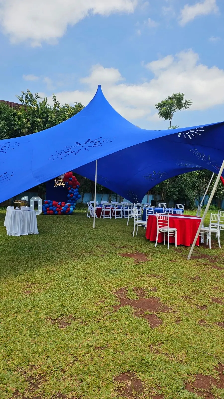 A spacious blue event canopy with dressed tables and white chairs on the lawn at Vipe Fun Park