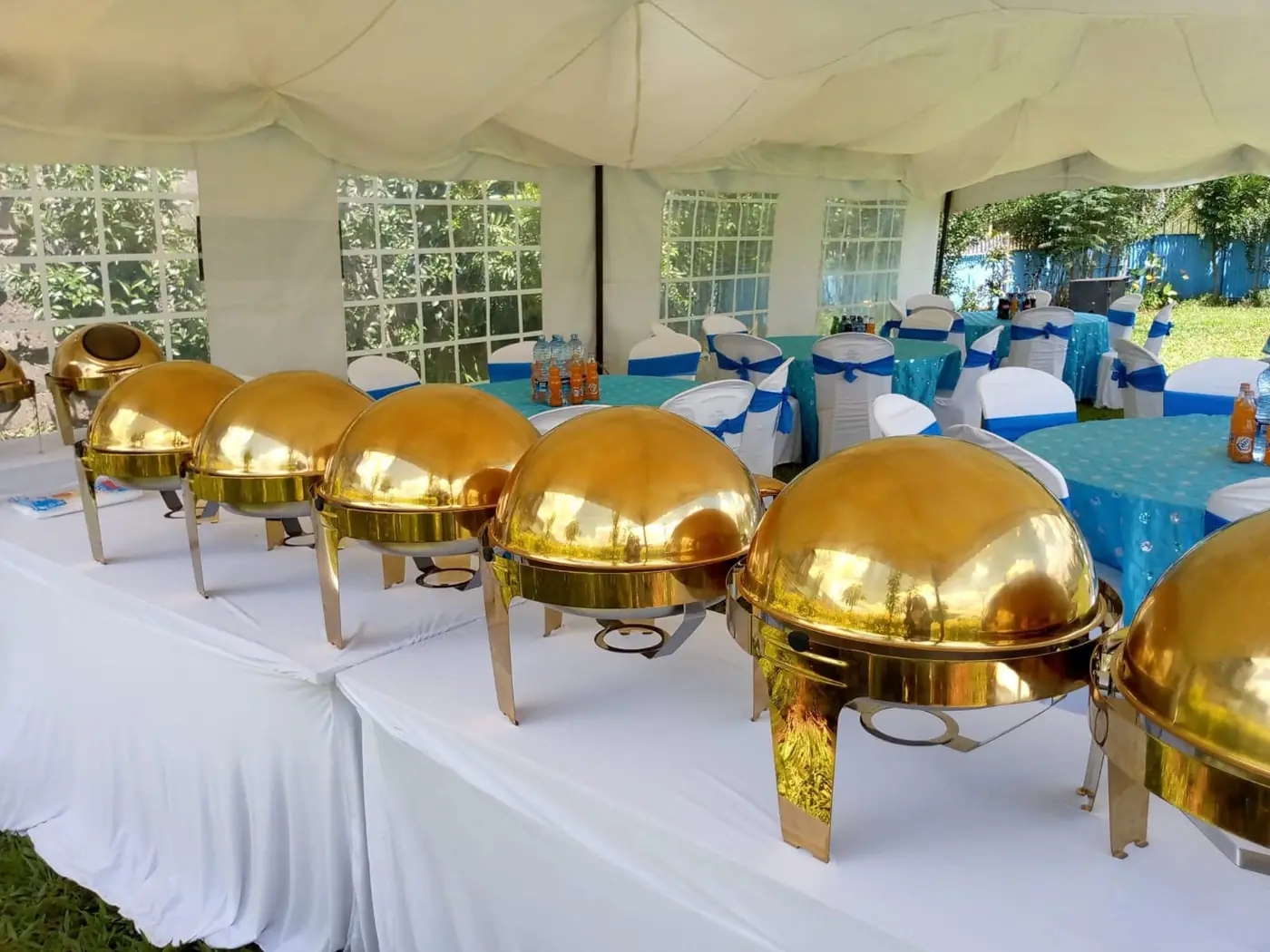 Covered serving dishes lined up on a dressed buffet table beside set tables at Vipe Fun Park