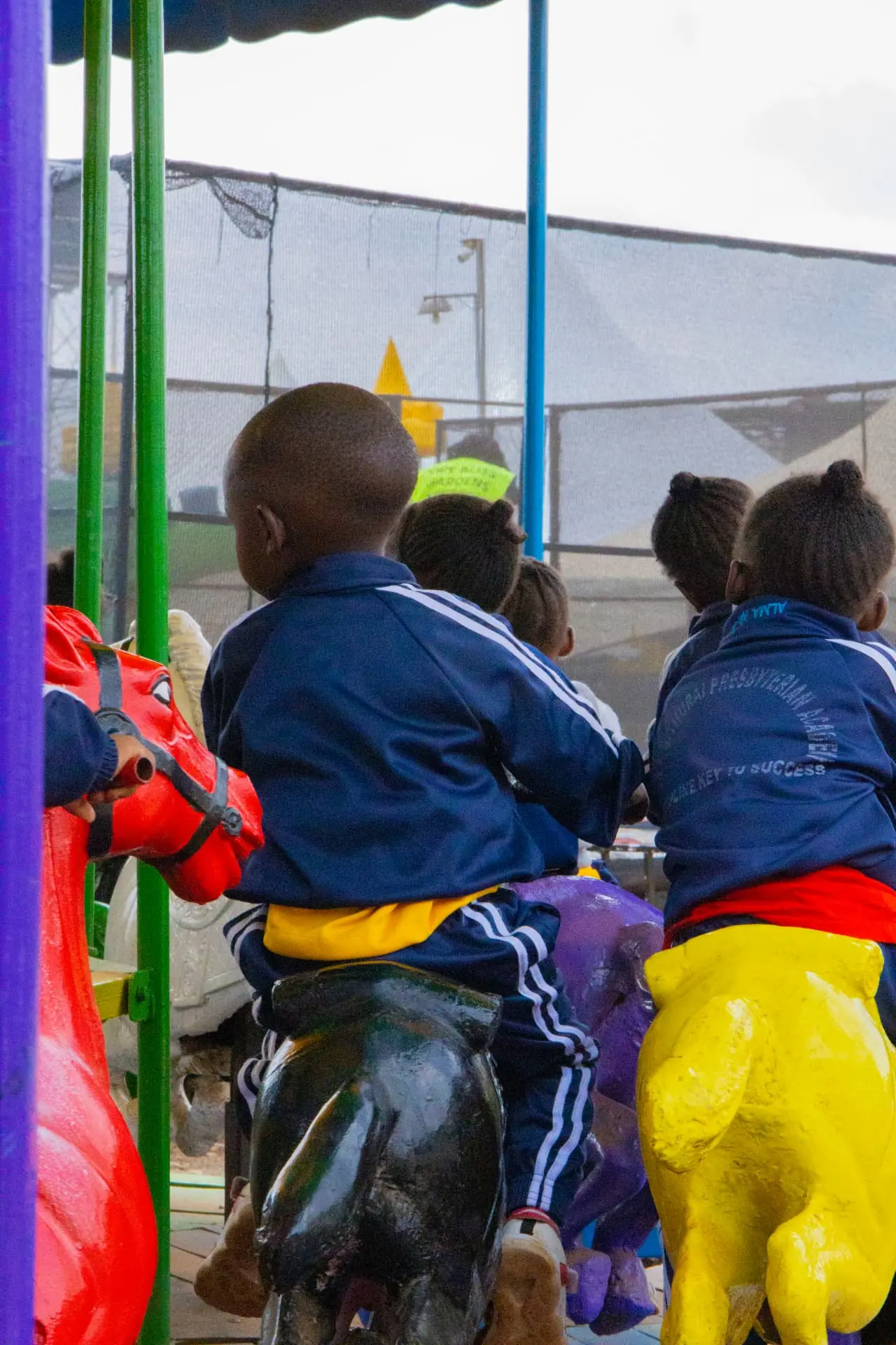 Children photographed from behind riding brightly coloured carousel animals at Vipe Fun Park