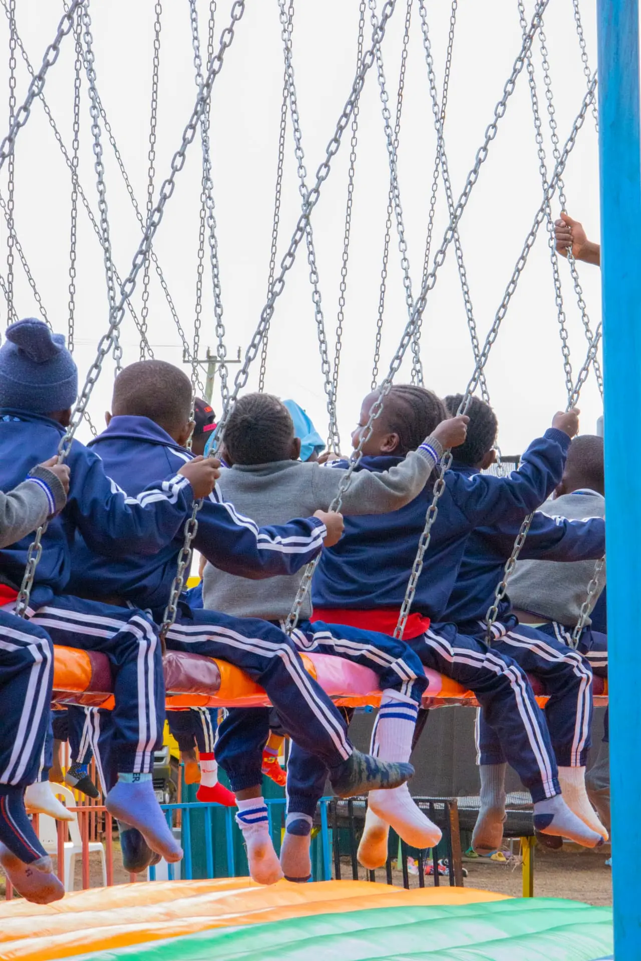 A school group photographed from behind while seated together on the swing ride